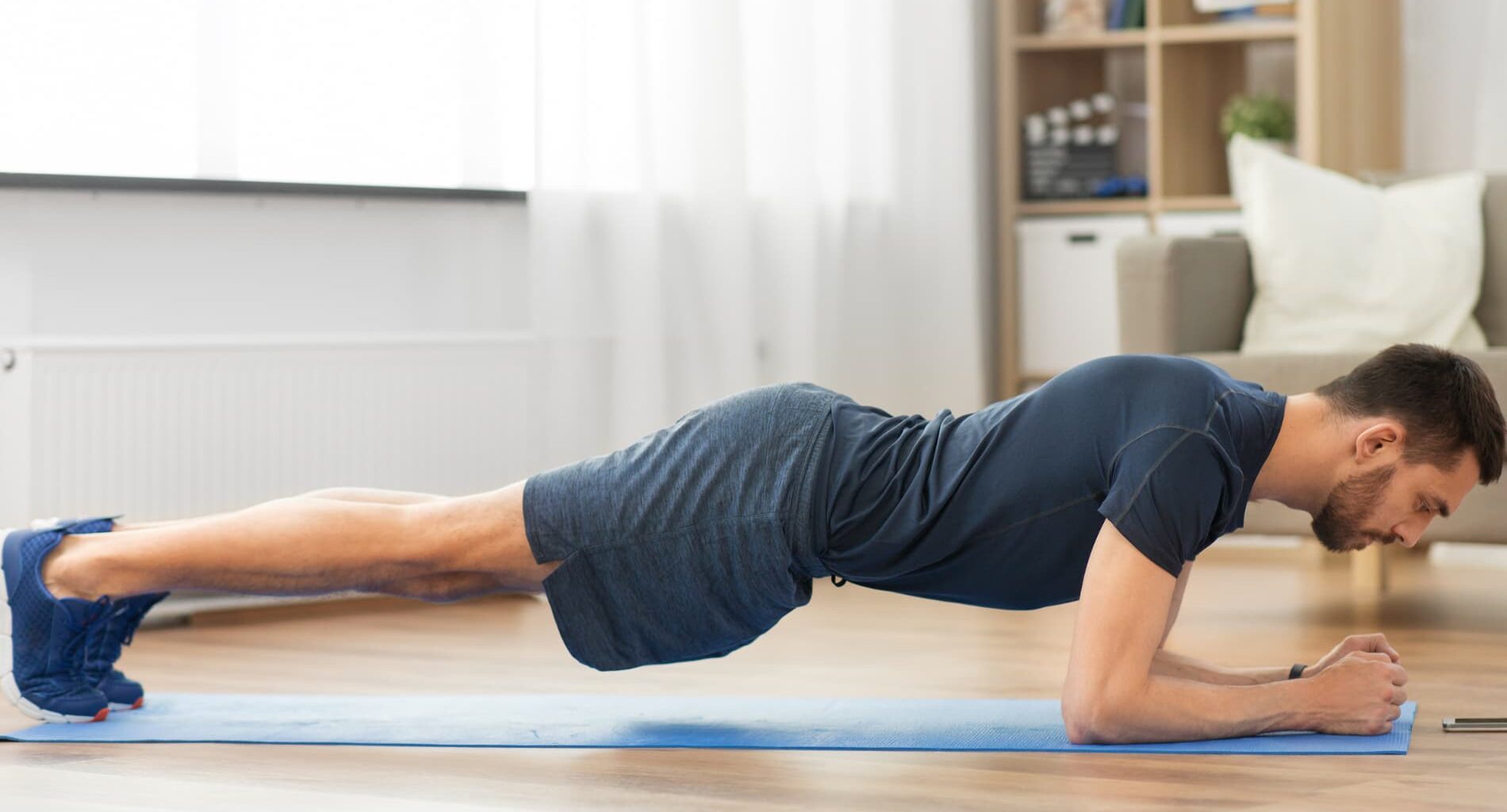 Um homem realizando um exercício de prancha para fortalecimento e prevenção de dor lombar, como parte de um program de fisioterapia.