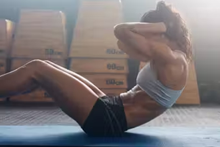 Jovem atlética fazendo exercícios abdominais para fortalecer o core, uma parte essencial da reabilitação da coluna e um tratamento personalizado.